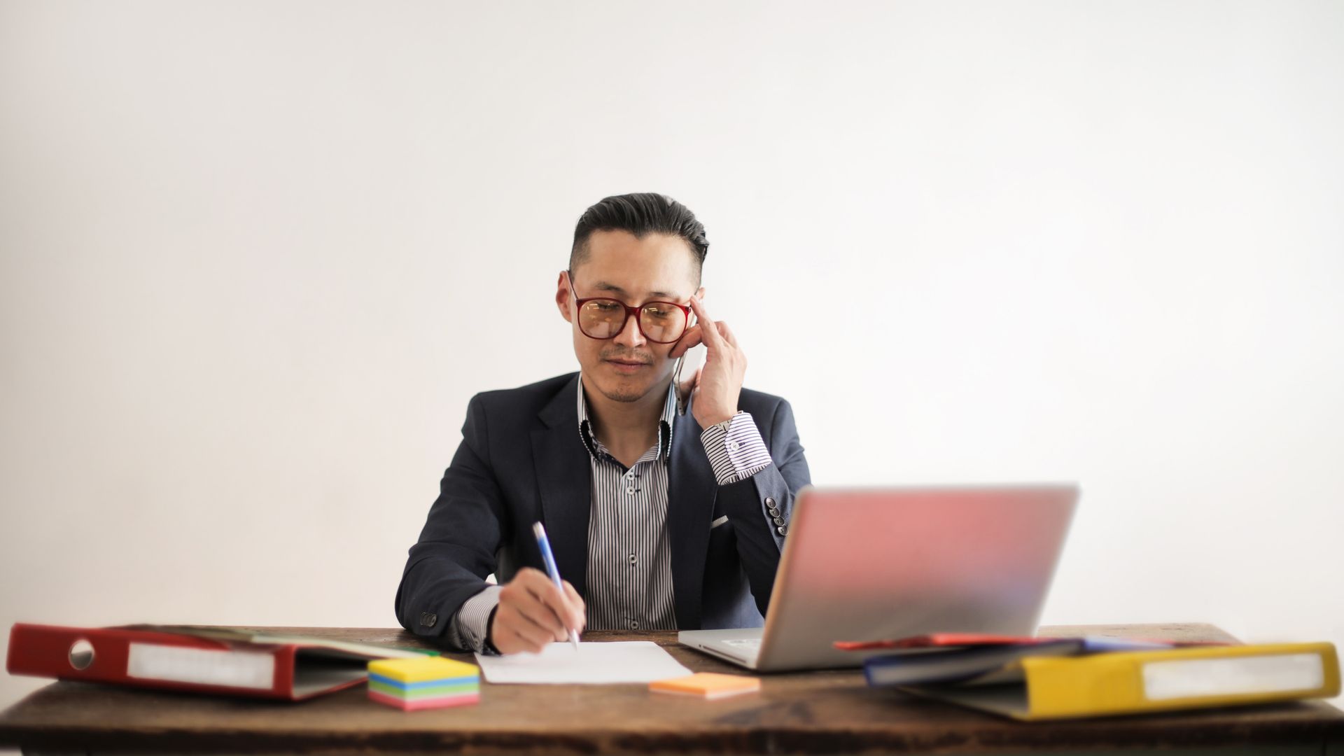 Modafinil for Entrepreneurs: Unleash Your Productivity Focused businessman multitasking at desk, engaged in a phone call and working on a laptop — modafinil for entrepreneurs