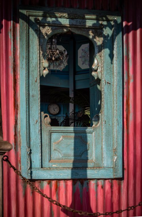Free An artistic, rustic blue window frame on a weathered pink wall, casting interesting shadows. Stock Photo