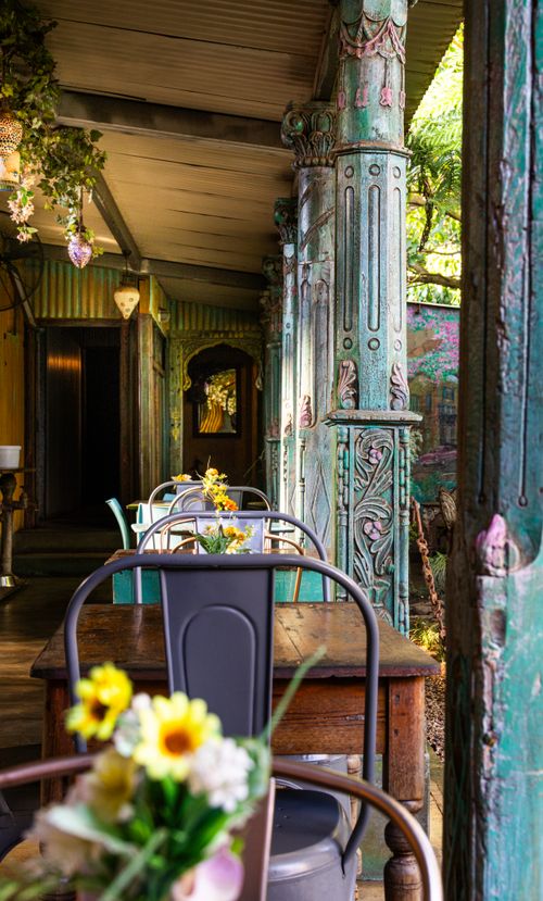 Free A cozy outdoor café with rustic wooden furnishings and floral decorations, exuding a warm, inviting ambiance. Stock Photo