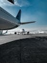 Low angle of various airplanes parked on airfield against blue sky on sunny day