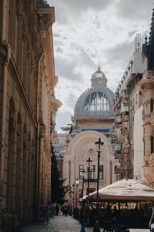 Free A charming street in Bucharest featuring historic architecture and a striking dome under a cloudy sky. Stock Photo