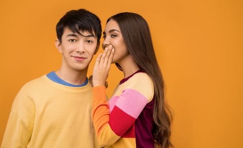 Free A young couple sharing a secret, with vibrant colors and a modern feel. Stock Photo