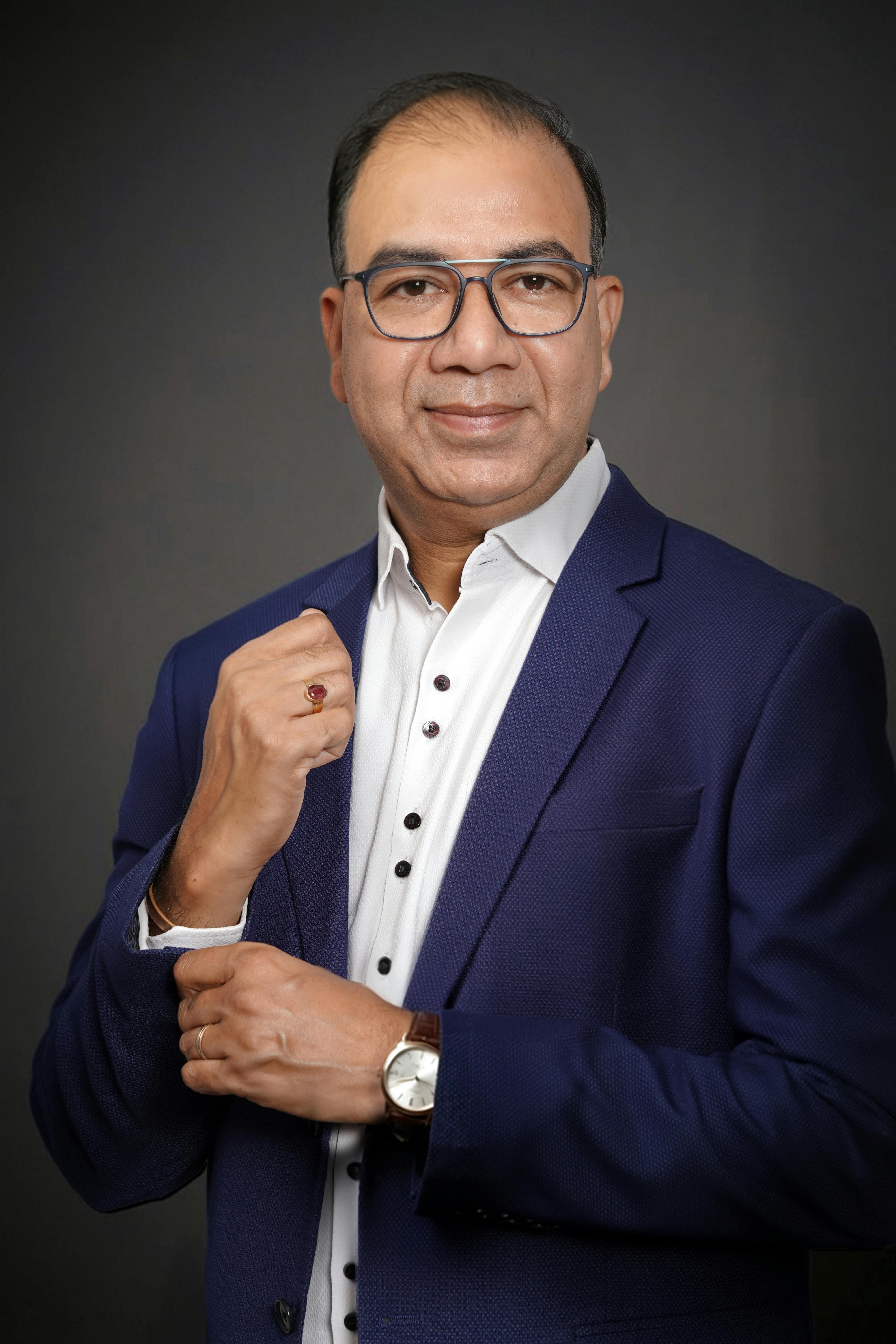 Professional portrait of a confident businessman in a blue suit against a dark background.