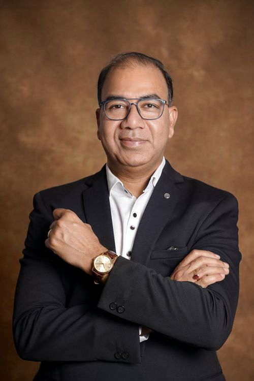 Free Portrait of a confident businessman in a suit with glasses and a watch against a brown background. Stock Photo