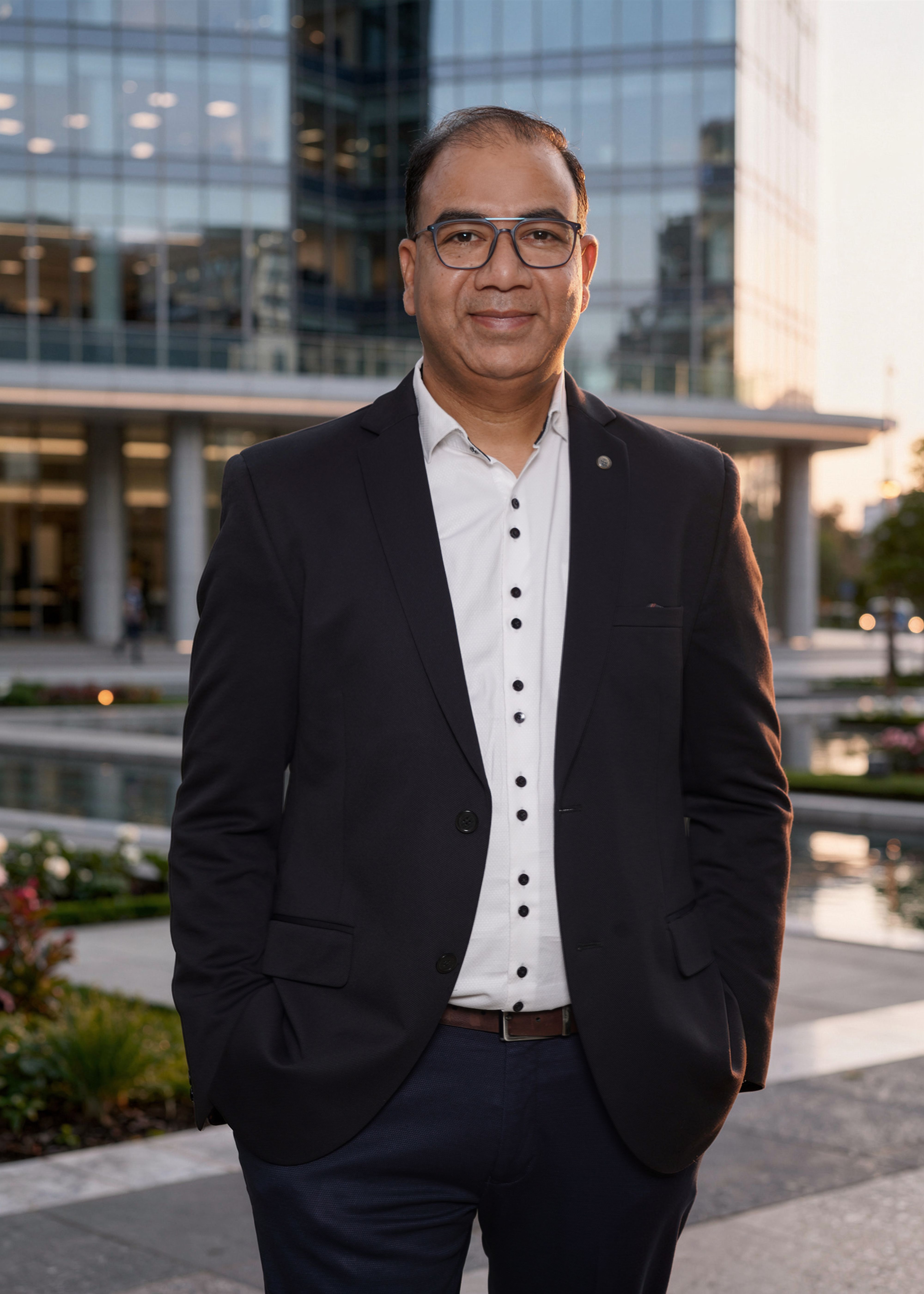Confident businessman standing outside a glass office building during the day.