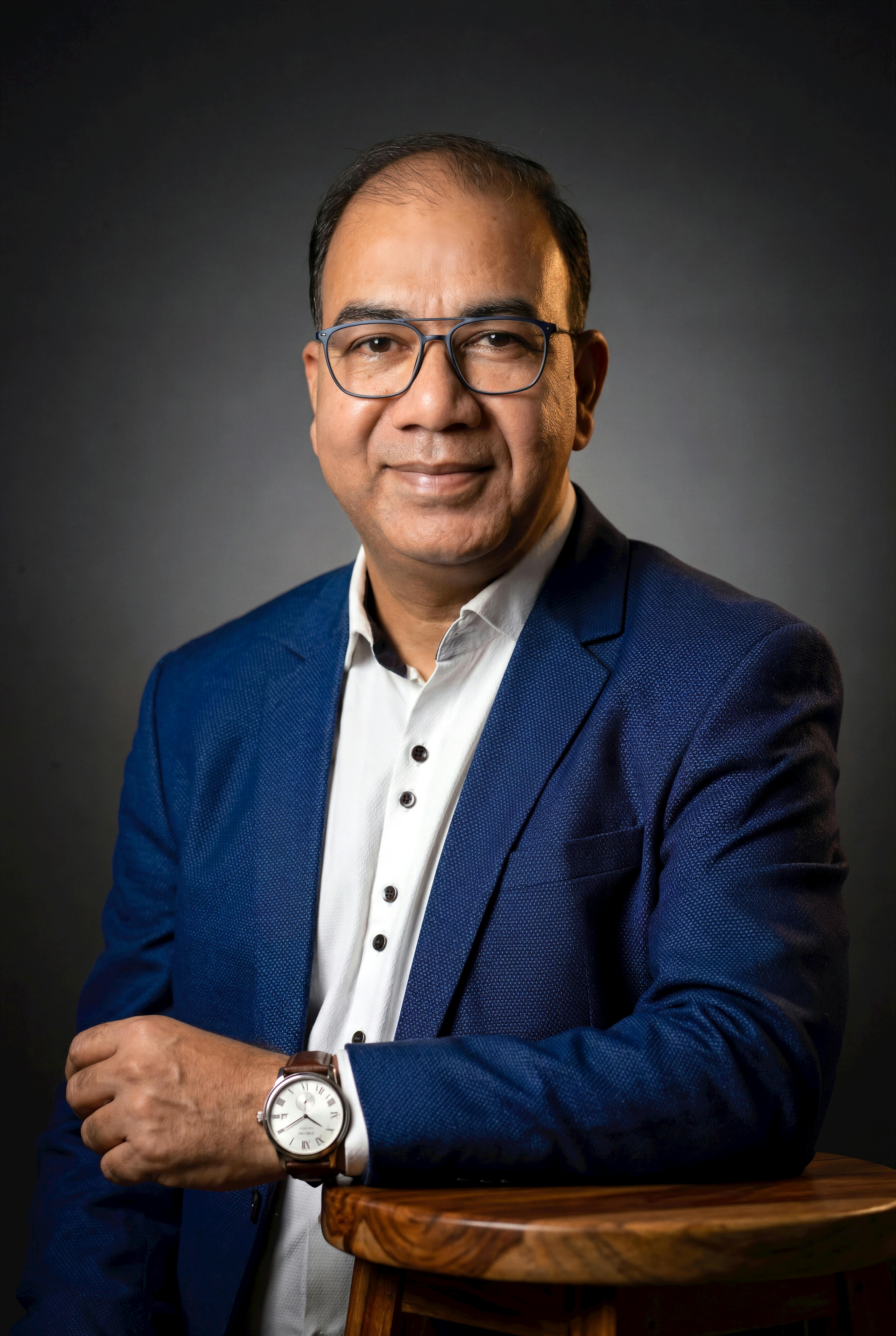 Confident man posing in business attire with glasses and watch, ideal for corporate use.