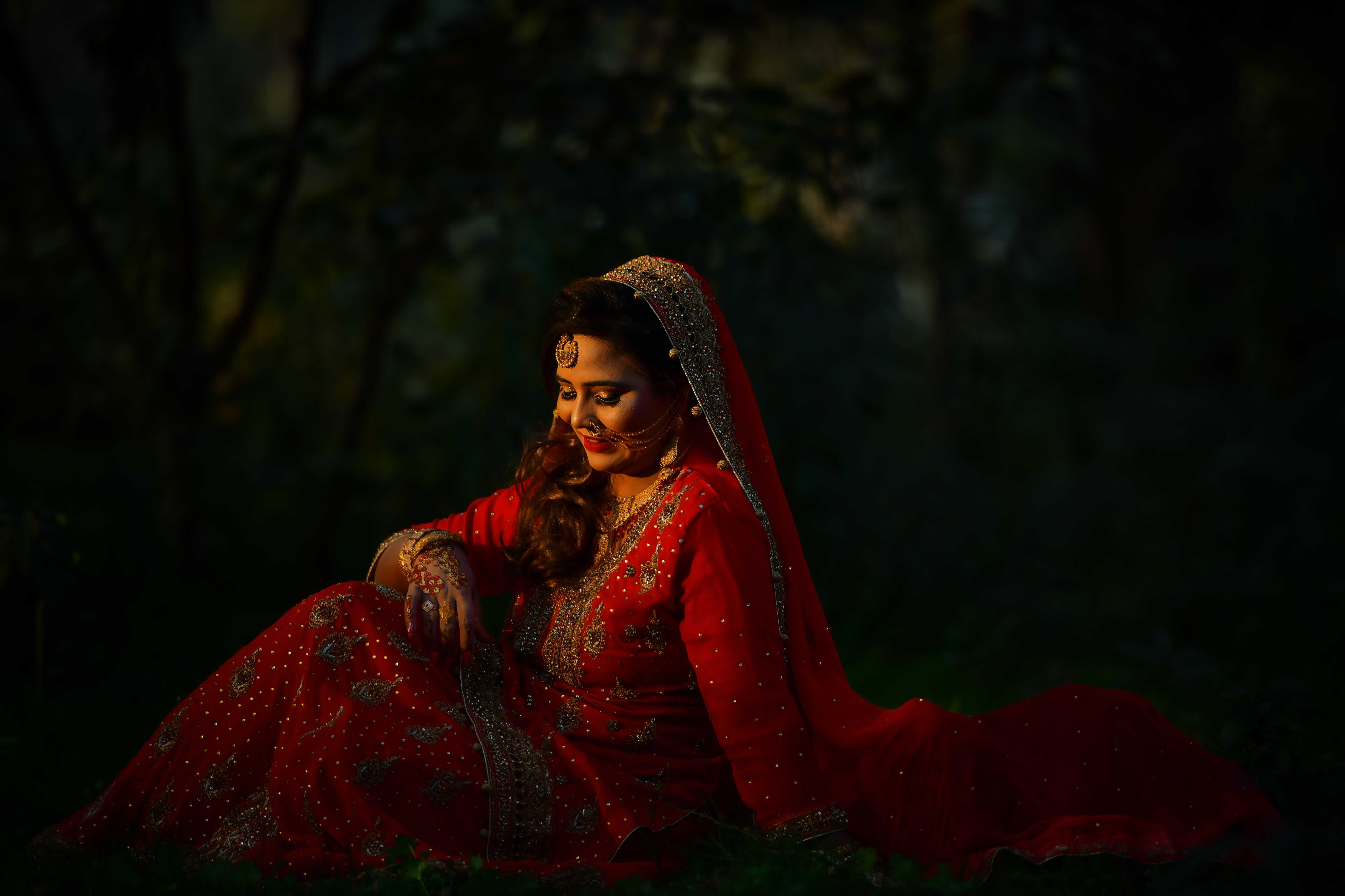 A stunning East Asian bride in traditional red dress posing gracefully outdoors.