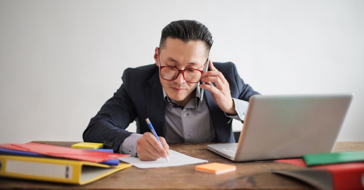 Business professional managing calls and laptop simultaneously — handling inbound leads from active Google Ads campaigns