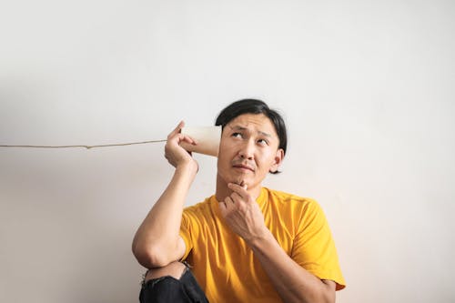 Hombre étnico Pensativo Escuchando Respuesta En El Teléfono De La Taza De Papel