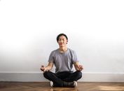 Photo of Man in Gray T-shirt and Black Jeans on Sitting on Wooden Floor Meditating