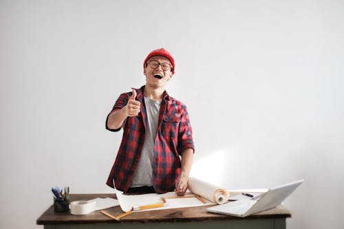 Free Laughing male constructor showing thumb up at working desk Stock Photo