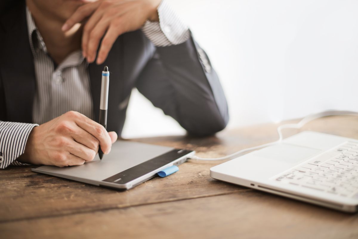 A designer refining slide visuals using a graphics tablet beside a laptop