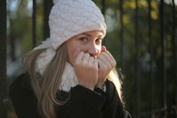 一位戴着针织帽和外套的女性，在户外冬日里温暖地微笑着
