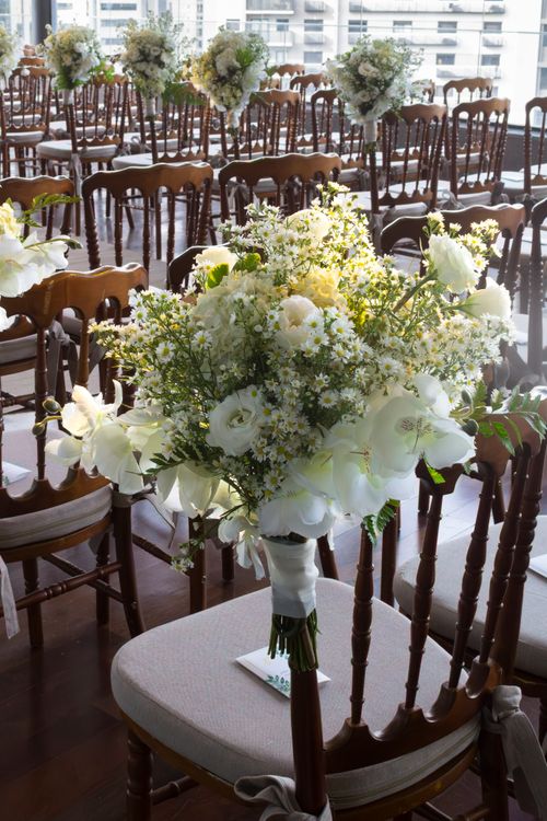 Free Beautiful white floral arrangements adorn chairs at a São Paulo wedding venue, creating an elegant atmosphere. Stock Photo