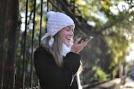 一位快乐的女士在冬日里穿着冬装，在户外使用智能手机，享受着阳光灿烂的日子