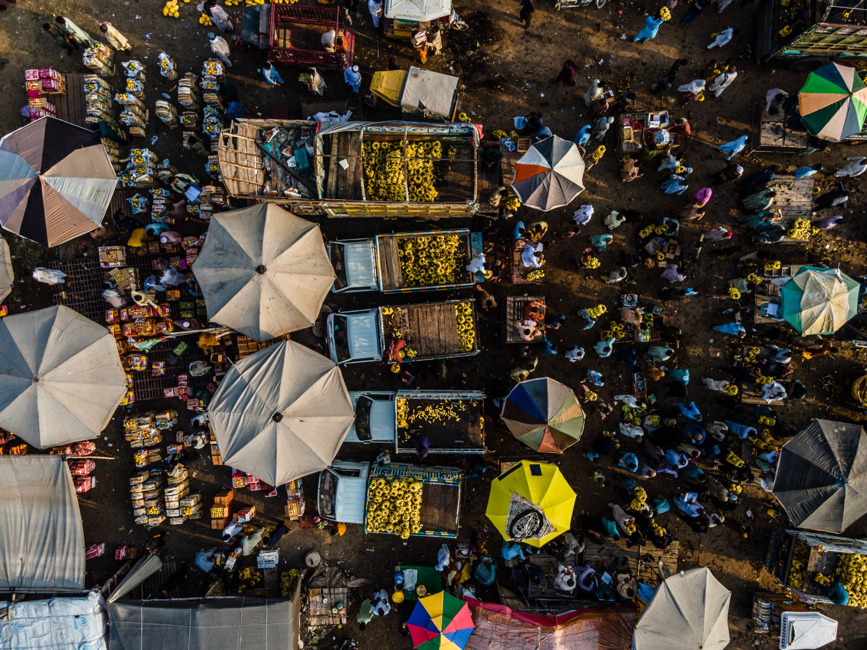 A lively aerial view of a thriving outdoor fruit market with vibrant colors and bustling activity.