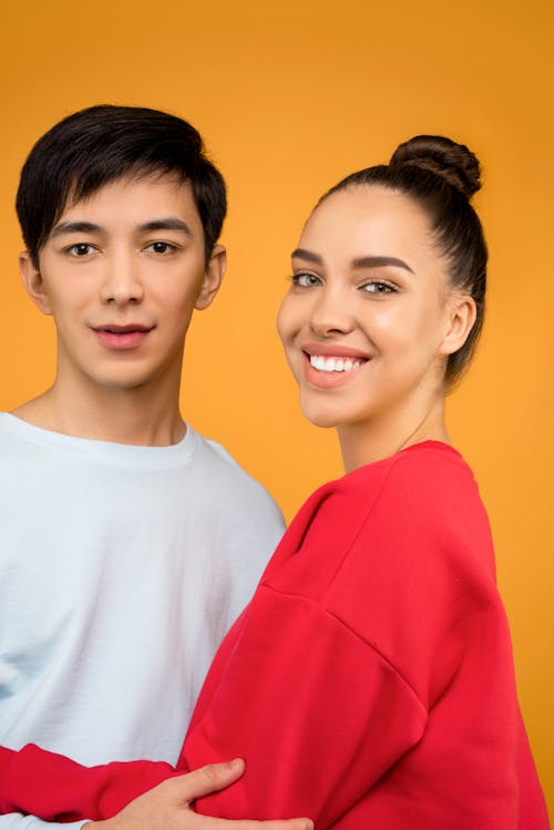 Portrait Photo of Man in White Crew Neck T-shirt Standing Beside Woman in Red Crew Neck T-shirt