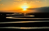 蜿蜒的河流在日落时分被拍摄下来，凸显了大自然的宁静之美与天空色彩的活力