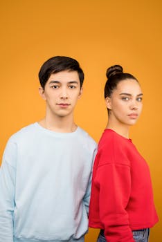 一对身着休闲装的男女站在充满活力的橙色背景前拍摄肖像