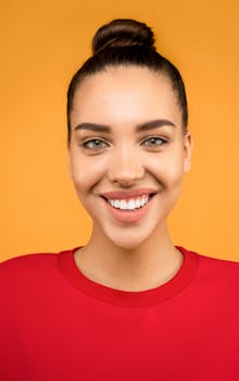 一位年轻女子面带微笑，在充满活力的橙色背景下，肖像洋溢着幸福