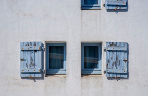 Free Charming blue shutters on a simple white wall, evoking a rustic and minimalist style. Stock Photo