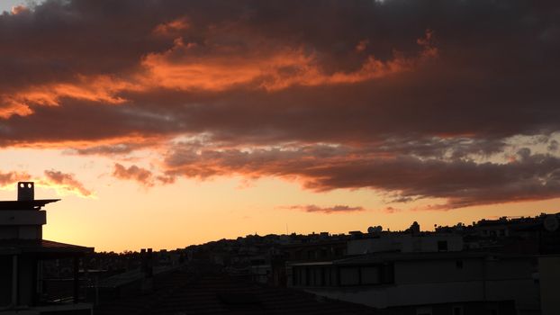 A stunning sunset with vibrant orange clouds over a city skyline.