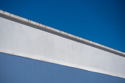 Free A minimalist shot of a white and blue building facade against a deep blue sky, creating a clean abstract look. Stock Photo