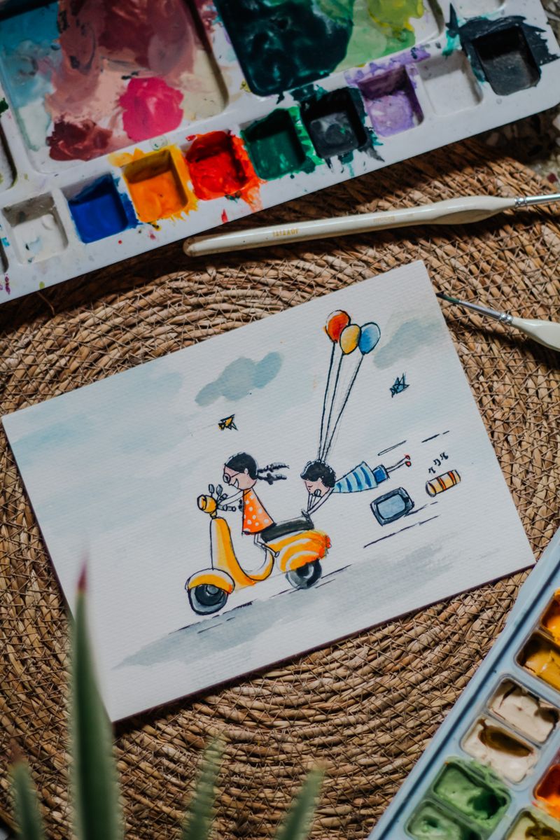 Artistic watercolor painting of children riding a scooter, surrounded by balloons and paint colors.