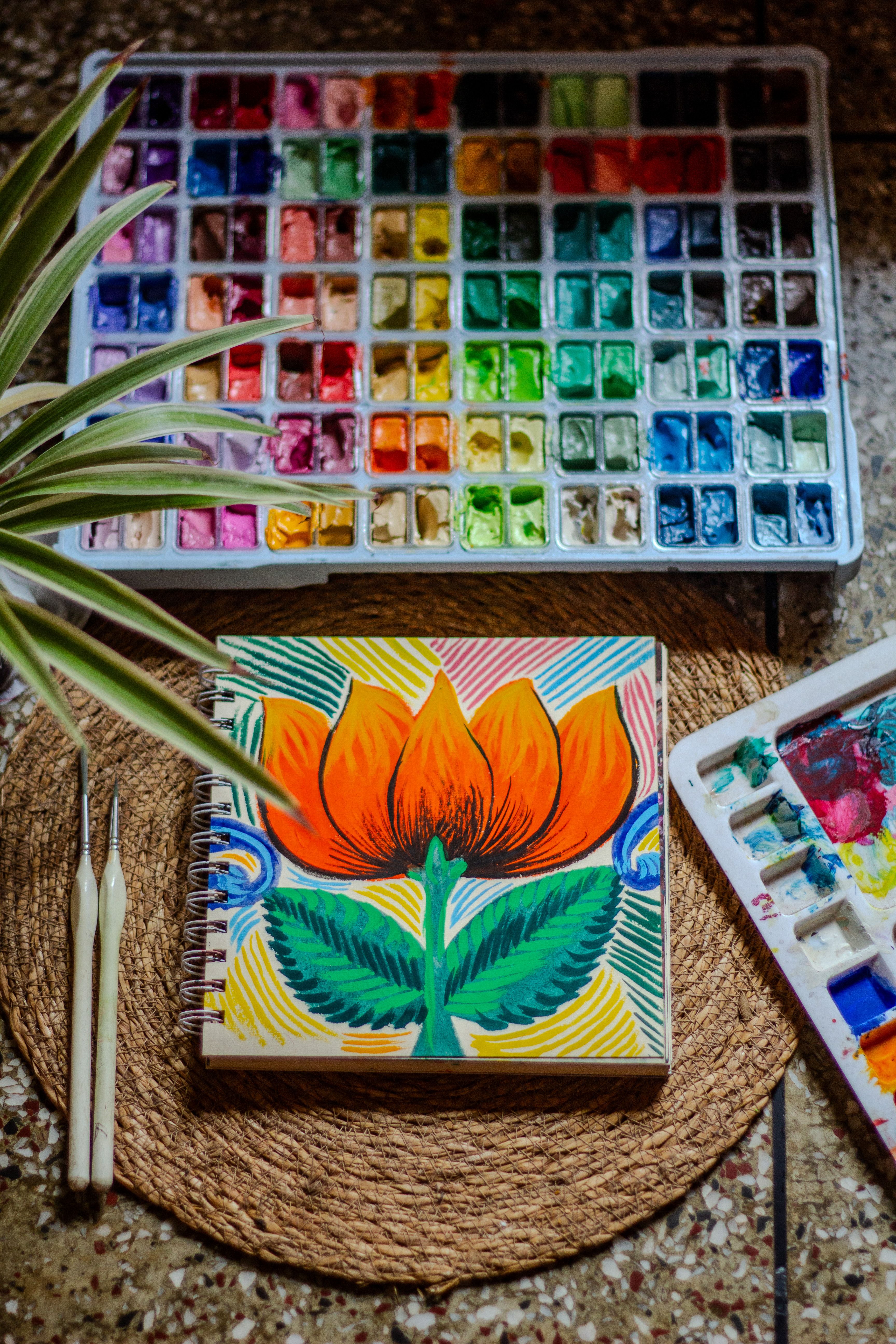 A painted lotus in a sketchbook beside a full pan set