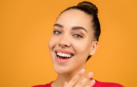 Portrait of a happy young woman with elegant makeup and hair against a vibrant yellow background.