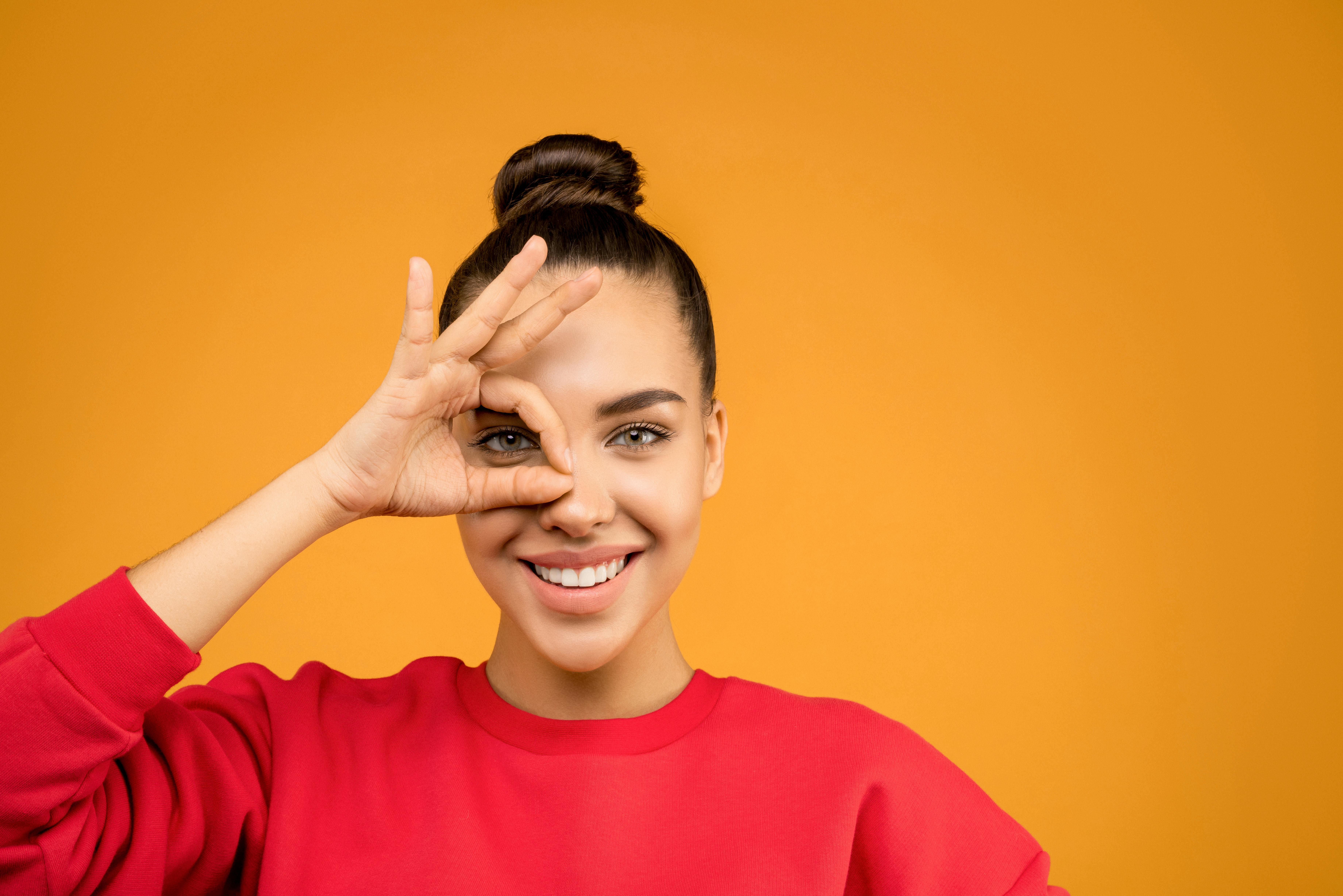 一位微笑的女人在充满活力的橙色背景下做出俏皮的手势
