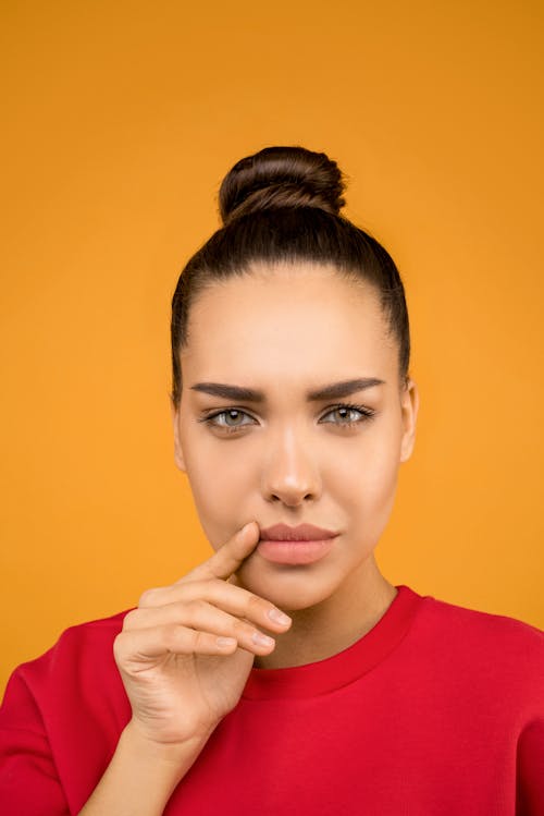 Close-up Portrait Photo of Woman in Red Crew Neck T-shirt Posing In Front of Orange Background