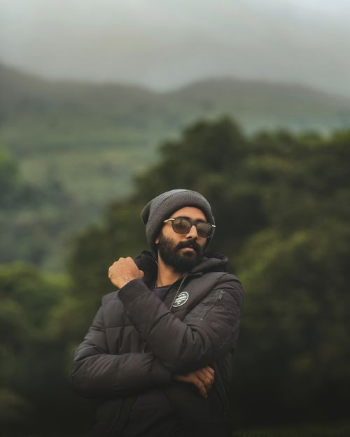 Free A man wearing sunglasses and a beanie in a forest setting on a misty day, showcasing casual style. Stock Photo