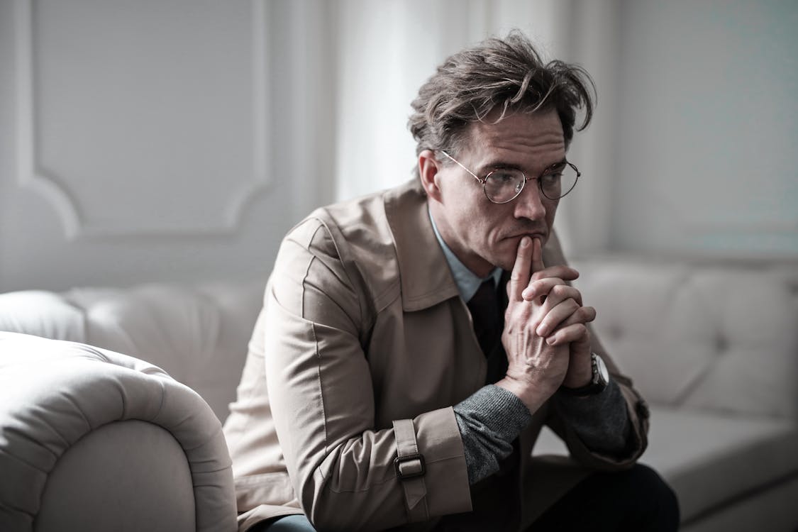 Free Man in Brown Suit Jacket Sitting on White Sofa Stock Photo