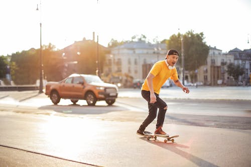 Man in Yellow Shirt and Black Pants Riding Skateboard