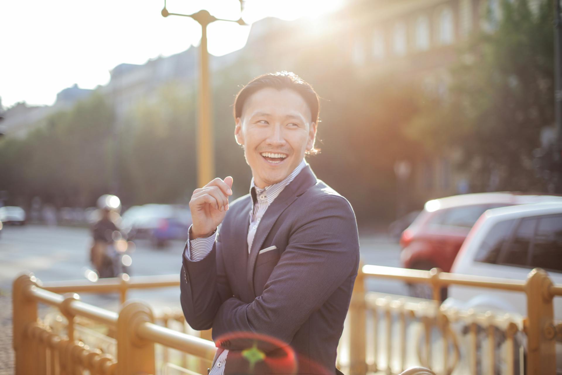 Portrait of a smiling businessman outdoors in an urban setting during sunset, exuding positivity and joy.