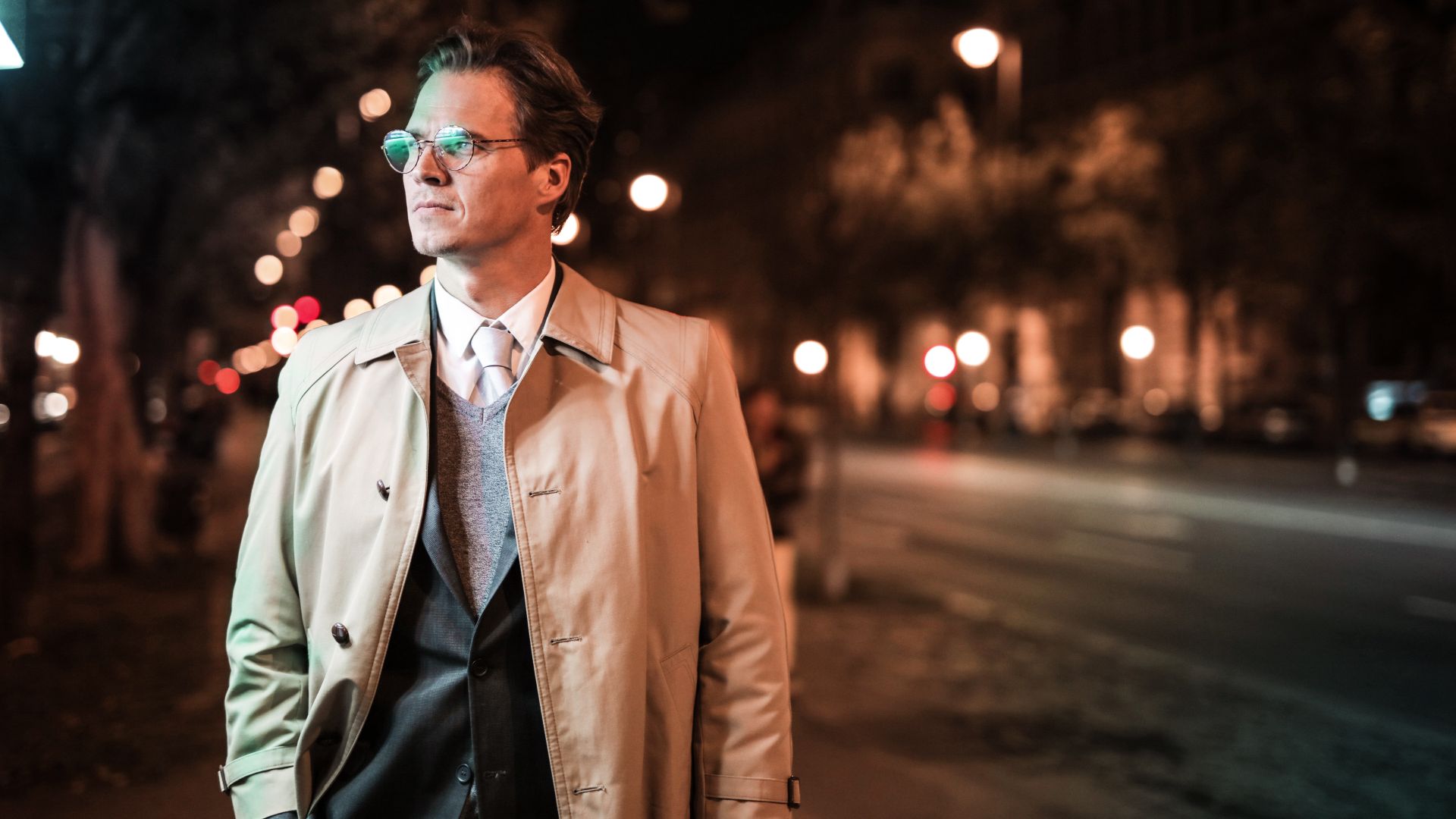 A man in a dark coat walking through the city at night