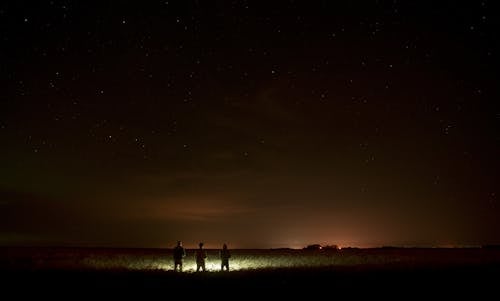 三人在夜間站在沙灘上的燈前