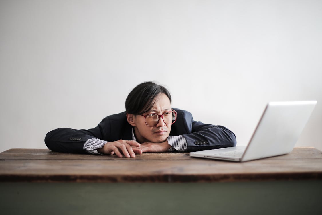 Bored formal man watching laptop at desk genius problem brainteaser