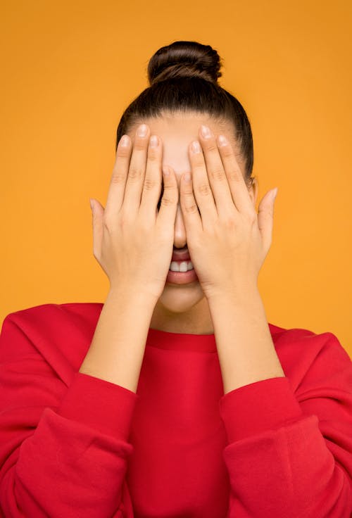 Woman in Red Long Sleeve Shirt Covering Face With Her Hands
