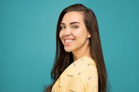 拥有深色长发的快乐女人在青色背景下微笑