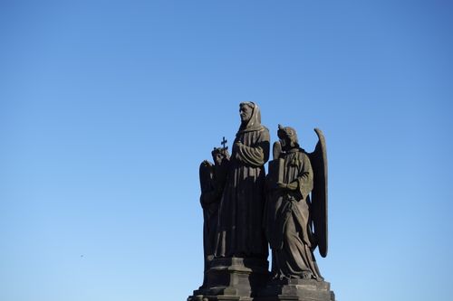 Free Dramatic statues on Charles Bridge in Prague under a clear blue sky, showcasing Gothic art. Stock Photo