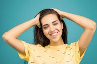 一位身穿黄色衬衫的开朗女子在青色背景下摆姿势