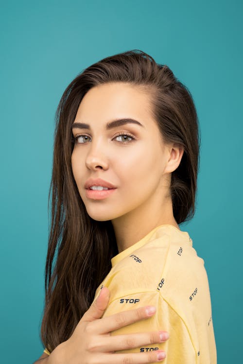 Portrait Photo of Woman in Yellow Top Posing In Front of Blue Background