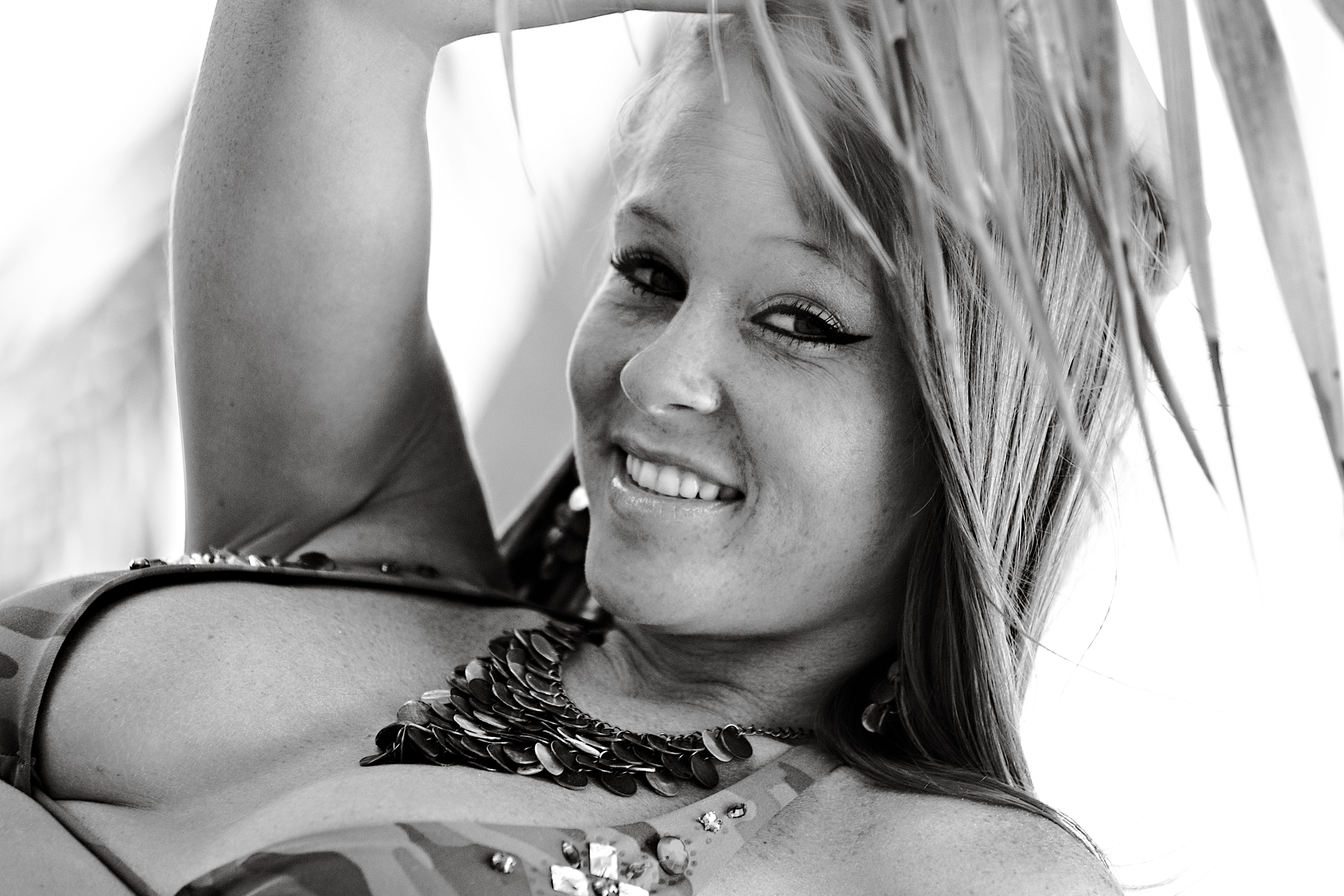 Beautiful black and white portrait of a smiling woman in beachwear with palm leaves, Miami Beach.