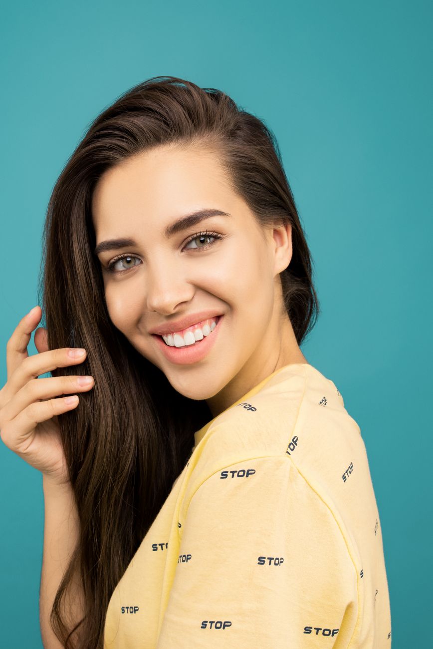 Portrait of a smiling woman posing against a blue background.