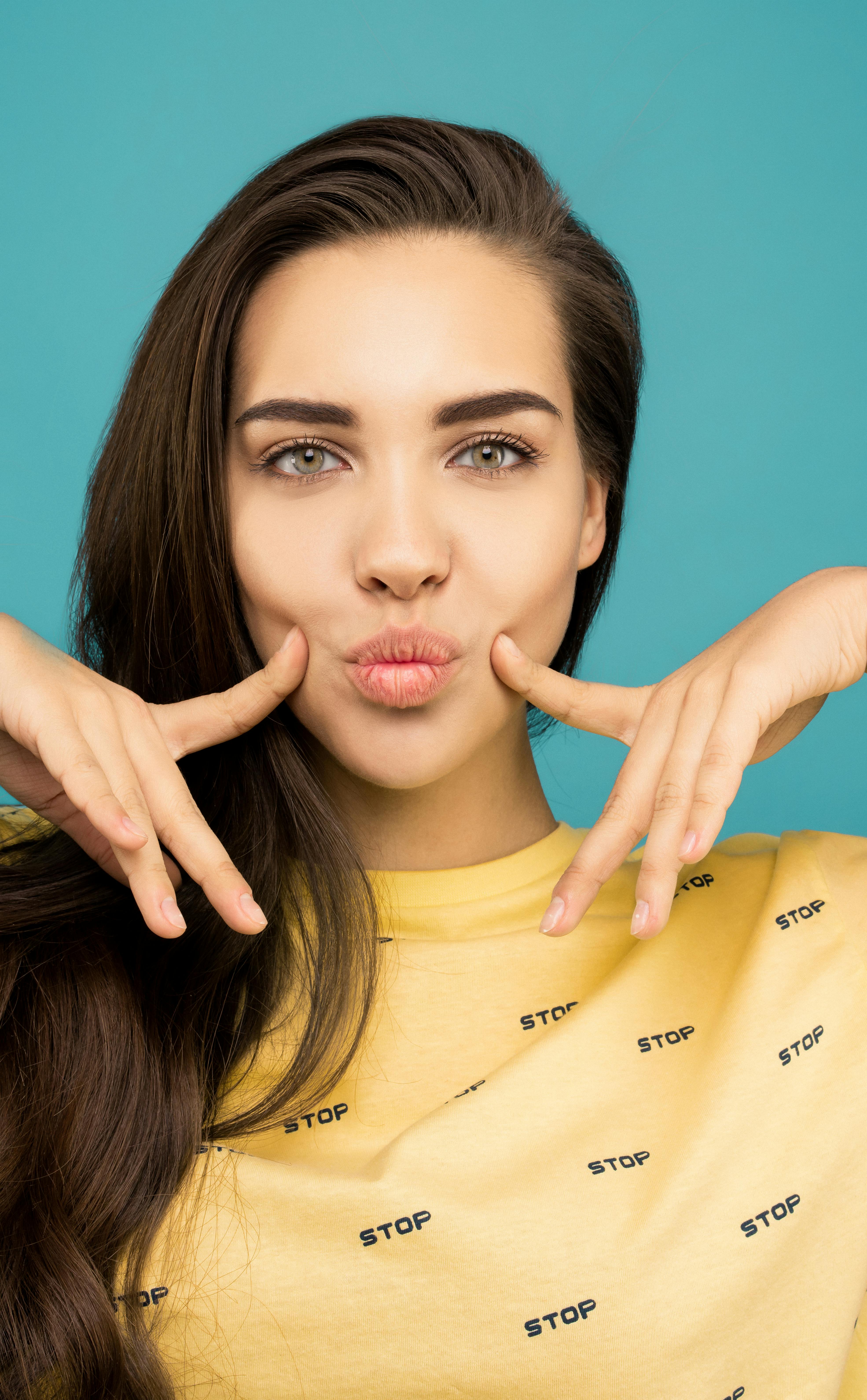 Portrait Photo of Woman in Yellow Sweatshirt Posing with Her Fingers on ...