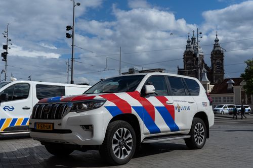 Free A Dutch police car in Amsterdam with historic architecture in the background. Stock Photo