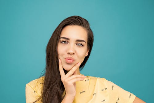Free Portrait Photo of Woman in Yellow T-shirt Posing with Her Hand on Her Chin Stock Photo