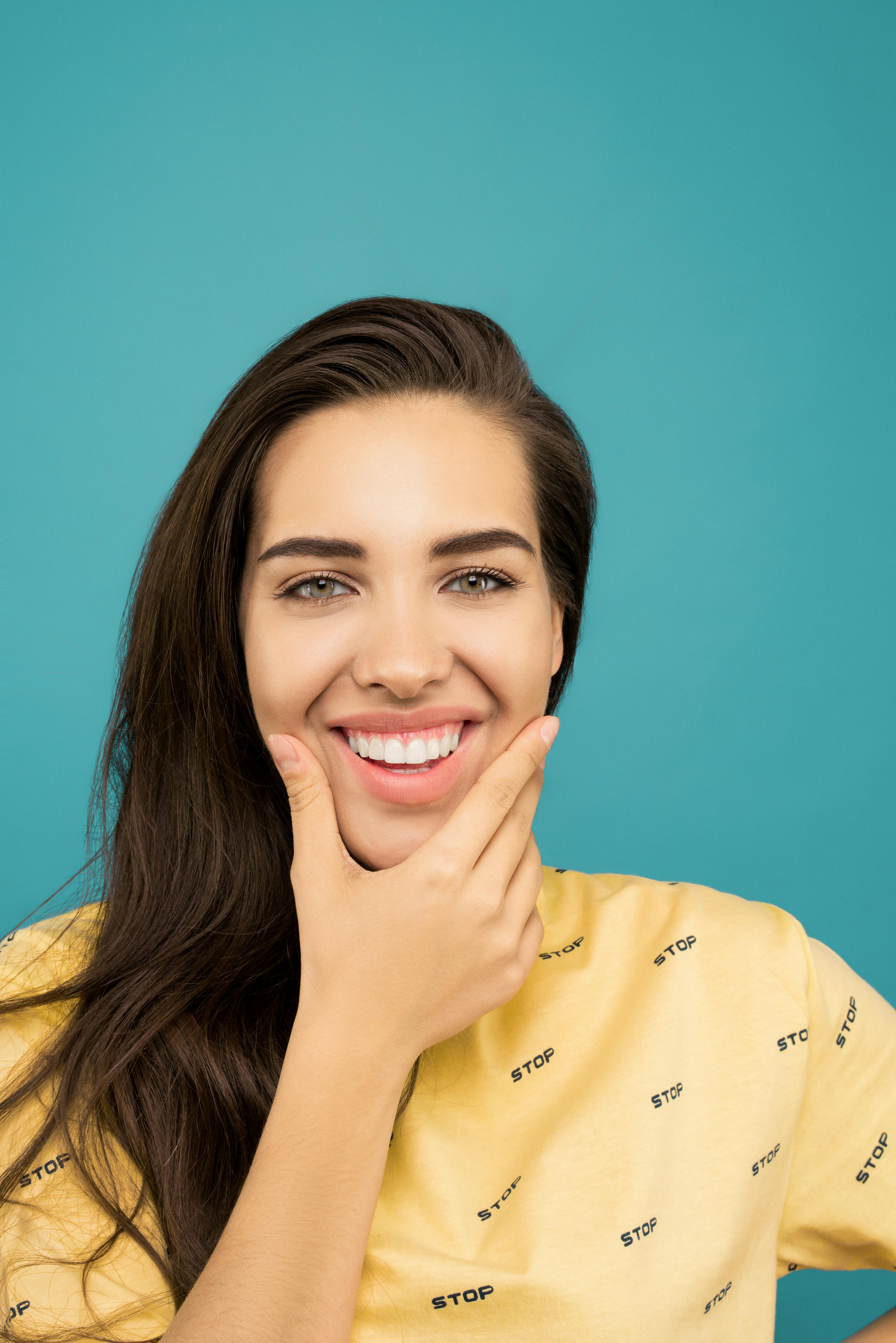 微笑的女人在青色背景下摆出手势